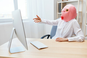 Angry businesswoman in pink fish mask screaming to desktop Raging after computer software crash error at workplace in modern office. Crazy director work online in financial corporation. Copy space