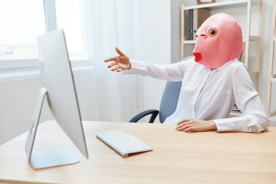 Angry businesswoman in pink fish mask screaming to desktop Raging after computer software crash error at workplace in modern office. Crazy director work online in financial corporation. Copy space