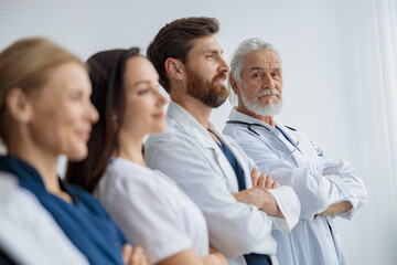 Group of professional doctors standing in a line keeping arms crossed at the modern clinic