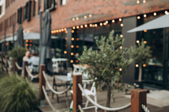 Blurred background of outdoor restaurant with abstract bokeh light. Outdoor cafe with tables and chairs