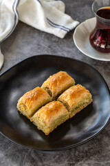 Turkish baklava. Baklava slices with pistachio on a dark background. Bakery products. Vertical view. Turkish cuisine. Close-up.
