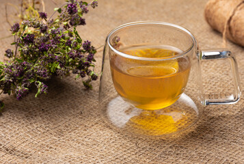 cup of herbal tea and bunch of dry thyme on wooden table