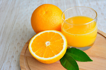 fresh oranges with glass of juice on wooden tray, close-up