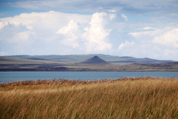 A lake and mountain with a blue sky and a white cloud. Natural landscape background.