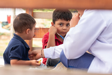 A pediatrician teaches a child to listen to his brother's heartbeat with a stethoscope. Curious and learning moment for children.