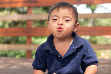 Portrait of a latin boy with Down syndrome blowing a kiss to the camera.