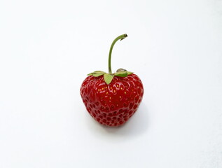 A single ripe red strawberry fruit in the shape of a heart on a white background.