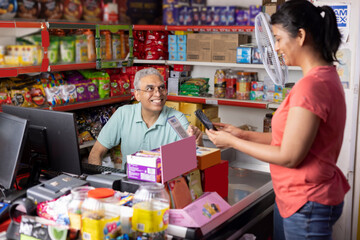 Woman grocery shopping paying by card at the supermarket to cashier