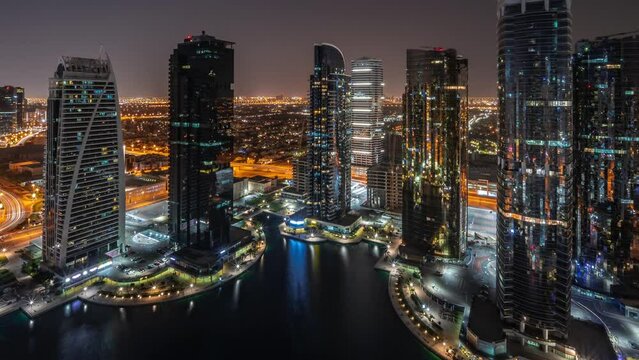 Tall residential buildings panorama at JLT district aerial timelapse during all night, part of the Dubai multi commodities centre mixed-use district. Lights turning off