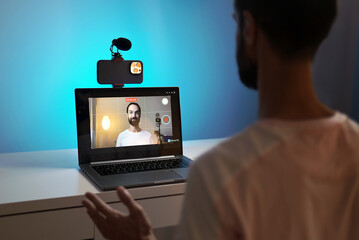 A young blogger records a video with himself on his phone in his studio.