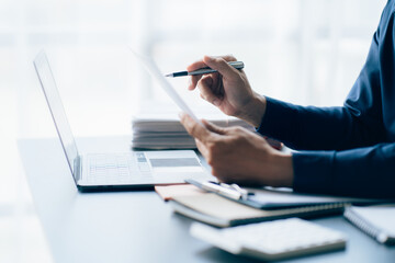 The hands of a male businessman are analyzing and calculating the annual income and expenses in a financial graph that shows results To summarize balances overall in office