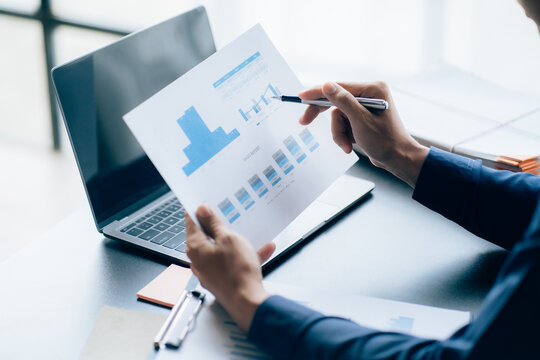The hands of a male businessman are analyzing and calculating the annual income and expenses in a financial graph that shows results To summarize balances overall in office