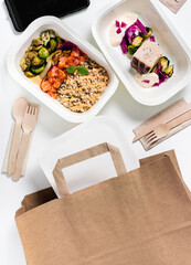 Collection of white plastic take away boxes with healthy food. Set of containers with everyday meals - meat, vegetables and law fat snacks on white background . wooden cutlery and a paper bag
