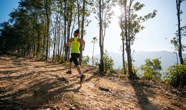 Woman trail runner running at sunrise tropical forest mountain peak