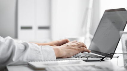 Closeup shot of businesswoman hands using laptop at office desk.