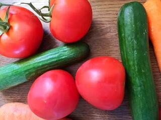 fresh vegetables on wooden table. Cucumbers, tomatoes, carrots lie side by side