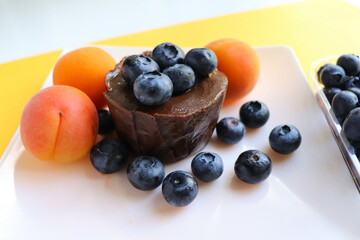 summer desserts. chocolate dessert with blueberries apricots on a white plate