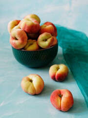Green bowl with peaches and three peaches scattered around