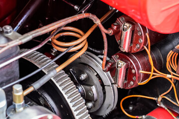 Fototapeta na wymiar Red vintage car simple engine, detail on pipes, cables and serpentine drive belt pulley