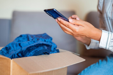 a girl opens a cardboard box with a parcel and items purchased from an online store at home in an apartment