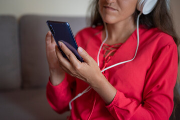 girl listens to music in headphones with a phone in her hands at home in the apartment