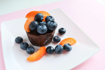 summer desserts. chocolate dessert with blueberries apricots on a white plate