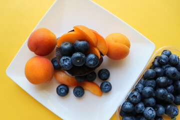 summer desserts. chocolate dessert with blueberries apricots on a white plate
