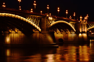 Fototapeta na wymiar the Margaret bridge in Budapest. perspective night view. bright, illuminated steel arches. reflection on the water. tourism and travel concept. transportation and structural design. evening photo. 