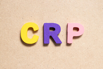 Color alphabet letter in word CRP (abbreviation of C-Reactive Protein Test) on wood background
