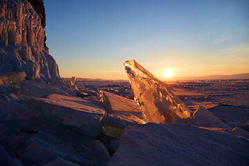 A beautiful sunset over the frozen Lake Baikal. Huge transparent ice floes, rocks in icicles.