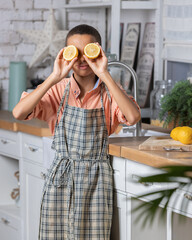 Black boy kid cooking fresh lemon on kitchen at home. African child shows tangerine eyes