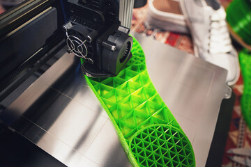 3D-printer produces a shoe sole with distinct inner structure from green plastic filament. top view...