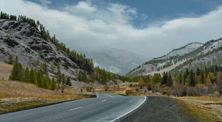 Fototapeta premium Russia. The South of Western Siberia, the Altai Mountains. The first autumn snow on the Chui highway near the village of Shebalino, surrounded by snow-capped mountains.