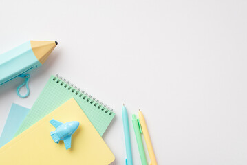 Back to school concept. Top view photo of school accessories blue pencil-case copybooks pens and plane shaped sharpener on isolated white background with copyspace