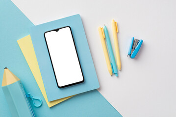 Back to school concept. Top view photo of smartphone over diaries pens stapler and blue pencil-case...