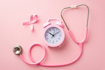 Breast cancer awareness concept. Top view photo of pink silk ribbon stethoscope and alarm clock on isolated pastel pink background