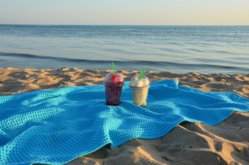 pieces of fruit in glasses on a blue blanket on the sandy beach. watermelon and melon at sunset....