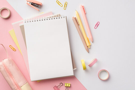 Back to school concept. Top view photo of girlish school supplies notepads pens stapler binder clips adhesive tape and pencil-case on bicolor pink and white background with blank space