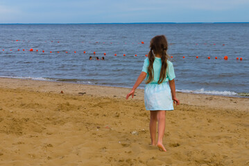 a girl with pigtails on the beach runs to the water on the sand
