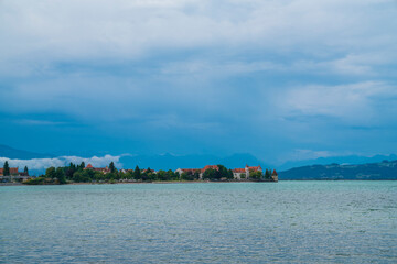 Germany, Lindau island city skyline in early morning misty mood at lake bodensee panorama view from water in summer