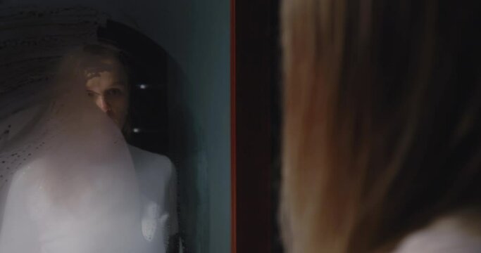 Depressed woman looking in steamy mirror