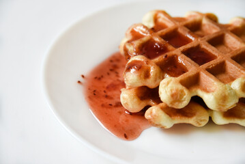 Viennese waffles with jam on a white plate. Delicious sweet breakfast with waffle.