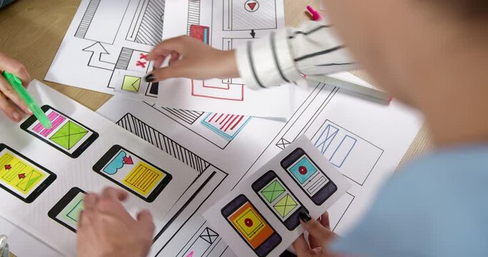 Web designers are developing a smartphone interface. Engineers create sketches of applications for mobile phones. User experience concept.