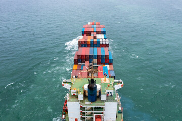 Fototapeta premium aerial back view of container ship carrying cargo container import export internatioonal and worldwide, business and industry goods logistic transportation by container ship in open sea,