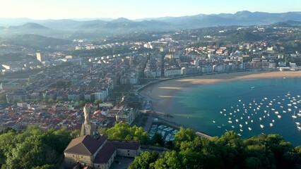 Unique cinematic perspective of the European city SAN SEBASTIAN. Situated in Spain -Vesque Country is a famous travel destination. Drone rotating around the Statue of Jesus. Panoramic view of the city