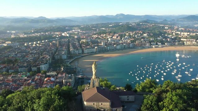 Unique cinematic perspective of the European city SAN SEBASTIAN. Situated in Spain -Vesque Country. Famous travel destination. Drone rotating around the Statue of Jesus. Panoramic view of the old city