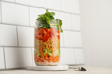 Trendy Fresh detox summer salad layered in a glass mason jar: yoghurt dressing, carrots, cucumber,...