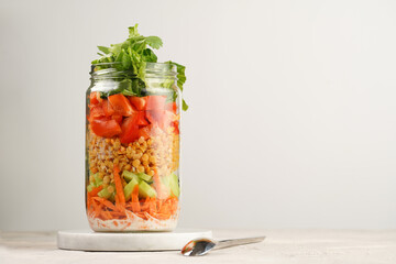 Trendy Fresh detox summer salad layered in a glass mason jar: yoghurt dressing, carrots, cucumber,...