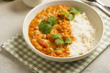 Indian red lentil curry with chickpeas, white rice and fresh cilantro - chana dal - in a white bowl on a green checkered kitchen towel