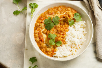 Indian red lentil curry with chickpeas, white rice and fresh cilantro - chana dal - in a white bowl on marble board
